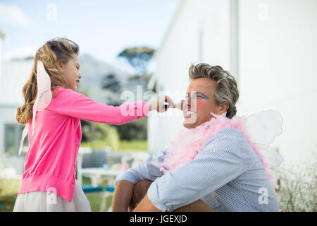 Costume fée mignon fille à mettre du maquillage sur son visage au jardin Banque D'Images