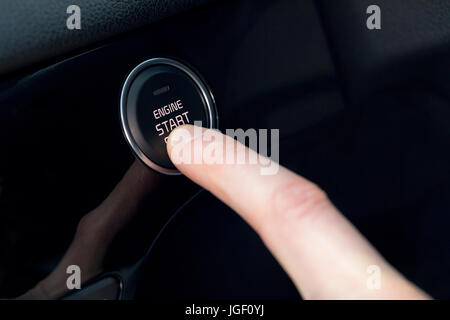 Ifinger recadrée en appuyant sur le bouton de démarrage de voiture Banque D'Images