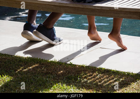 La section basse de père et fils assis sur un banc dans le jardin Banque D'Images