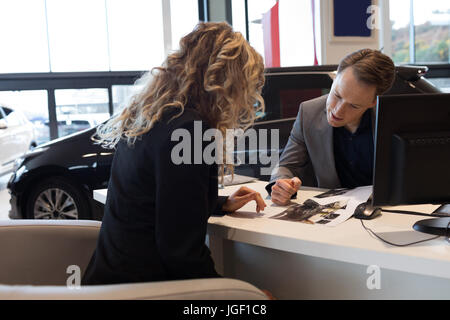 Vendeur montrant le document au client car showroom Banque D'Images