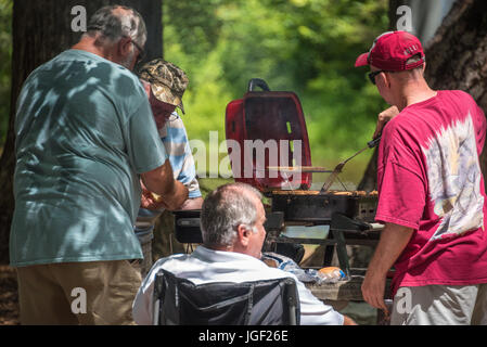 Men grilling burgers et hot-dogs pour une réunion de famille le long de la rivière Chattahoochee à Helen, la Géorgie. (USA) Banque D'Images