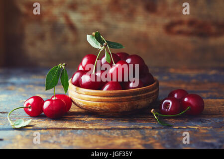 Les cerises dans un bol sur une table en bois. Cerises fraîchement récoltées dans un bol sur une table en bois. Banque D'Images