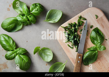 Feuilles de basilic frais haché. Le basilic frais sur une planche à découper en bois. Banque D'Images