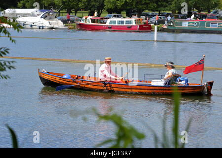 Les rameurs et les visiteurs profiter de la dernière journée de régate royale de Henley 2017, un couple de personnes âgées l'aviron dans un bateau en bois classique. Banque D'Images