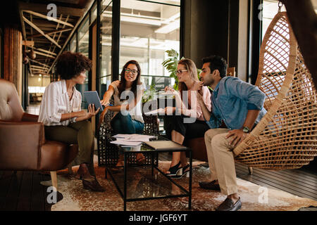L'équipe d'entreprise de discuter de nouvelles idées sur tablette numérique. Réunion de l'équipe de l'entreprise créative dans un bureau moderne. Banque D'Images