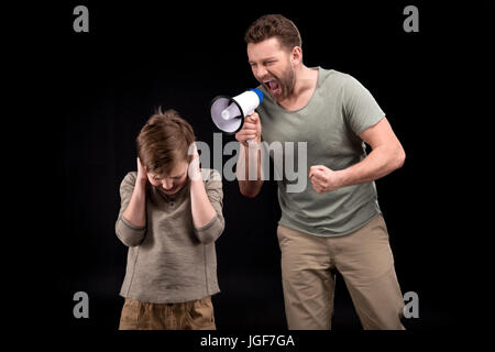 Père en colère avec mégaphone hurler à peur petit garçon fermer les oreilles, les problèmes de famille concept Banque D'Images