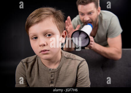 Père avec mégaphone hurler à peur petit fils, les problèmes de famille concept Banque D'Images