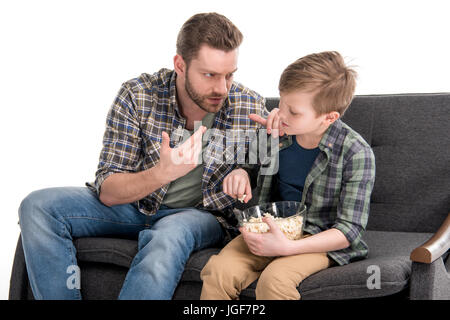 Parler avec père fils assis sur un canapé et eating popcorn de bol, les problèmes de famille concept Banque D'Images