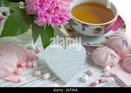 Fleurs de pivoines tasse de thé rose guimauve coeurs en rotin blanc sur un fond de bois - image Banque D'Images