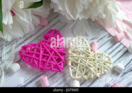 Coeurs en rotin fleurs pivoines marshmallow sur un fond en bois blanc - stock image Banque D'Images