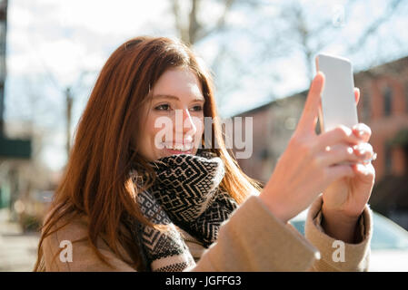 Caucasian woman wearing scarf posant pour selfies téléphone cellulaire Banque D'Images