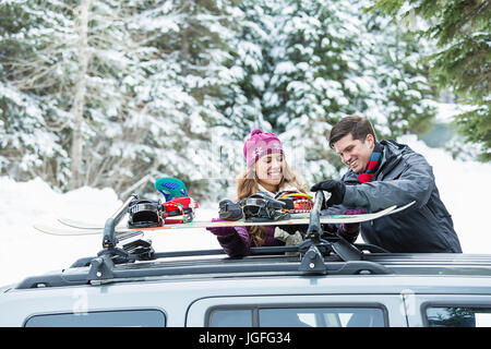 Caucasian couple contrôle de snowboards en voiture de toit Banque D'Images