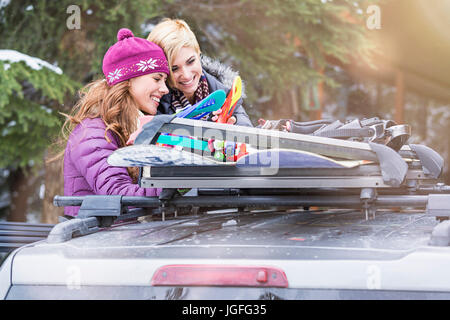 Les femmes de race blanche contrôle de snowboards en toit de voiture Banque D'Images