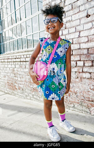 Smiling Black Girl standing on sidewalk portant robe et sac à main Banque D'Images