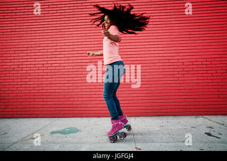 Black woman dancing sur patins à on sidewalk Banque D'Images