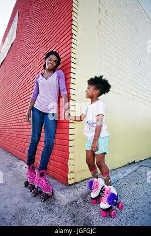 Mère et fille noir portant des patins à holding hands Banque D'Images