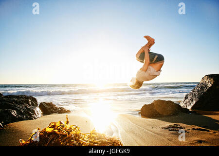 Caucasian man performing backflip on beach Banque D'Images