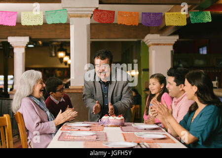 Family celebrating birthday of older man in restaurant Banque D'Images
