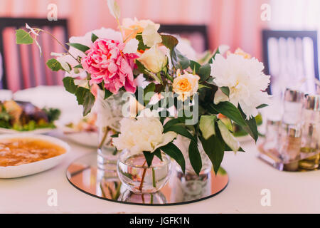 Belles fleurs bouquet de roses et de pivoines colorées dans le mini-vases) sur l'ensemble de tables de mariage. Banque D'Images