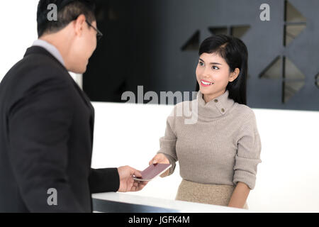 Belle fille asiatique à la réception d'un hôtel en contrôle avec d'affaires. Banque D'Images