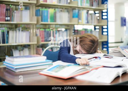 Libre ou d'une jeune femme avec de nombreux livres de dormir pendant la lecture réservez préparer l'examen pratiqué à l'université à la bibliothèque. Les gens, l'éducation, sessio Banque D'Images