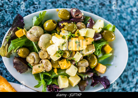 Gros plan macro de salade sur la plaque dans le aux champignons, fromage, olives et carrés verts Banque D'Images