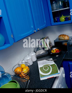 Armoires de cuisine en bois bleu au-dessus de sol carrelé blanc et gris plan de refoulement Banque D'Images