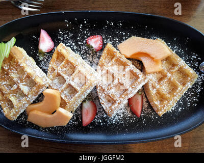 Belgique gaufres avec des fruits et du sucre en poudre sur assiette petit-déjeuner, overhead view Banque D'Images