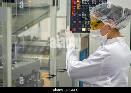 Un technicien femelle à l'aide du panneau de commande de comprimé machine d'emballage. L'industrie pharmaceutique. Banque D'Images