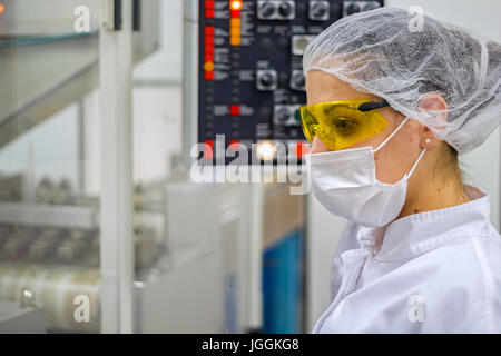 Technicien pharmaceutique en utilisant le panneau de contrôle du comprimé machine d'emballage. L'industrie pharmaceutique. Banque D'Images