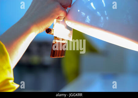 Technicien de laboratoire inspecte visuellement pour flacons et d'ampoules dans les particules et liquides contenant des défauts. Banque D'Images