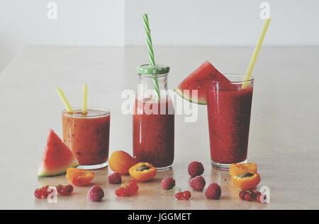 La vie toujours avec l'été dans des boissons smoothie verres sur la table décorée de fruits et de baies - pastèque, abricot, framboise, groseille rouge Banque D'Images