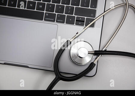 Ordinateur portable et stéthoscope sur fond gris, à l'horizontale. Banque D'Images