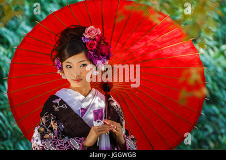 Femme japonaise dans une robe kimono traditionnel avec un parapluie rouge Banque D'Images