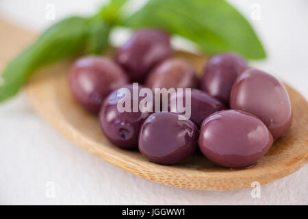 Close up of brown olives en cuillère en bois sur la table Banque D'Images