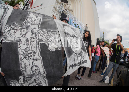 Pèlerins à un vigile pour martyriser l'archevêque Oscar Romero déploient un bandeau peint à l'extérieur de la cathédrale métropolitaine de San Salvador. La bannière dessins dépeignent l'amour inébranlable Romero et de soutien pour les pauvres et les travailleurs agricoles. De petits paysans. El Salvador se prépare pour la cérémonie de béatification et de masse annonçant la béatification de l'archevêque Oscar Romero. L'archevêque a été immolé sur l'autel de son église de la Divine Providence par un homme armé de l'aile droite en 1980. Oscar Arnulfo Romero y Galdamez est devenu le quatrième Archevêque de San Salvador, en remplacement de Luis Chavez, et s'est prononcée contre la pauvreté, l'i Banque D'Images