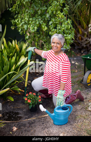 Portrait de femme agenouillée sur terrain tout en faisant du jardinage dans la cour Banque D'Images