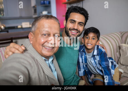 Close up of smiling family avec bras autour de sitting on sofa at home Banque D'Images