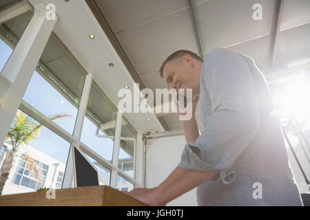 Low angle view of designer talking on smart phone while standing at desk in office Banque D'Images