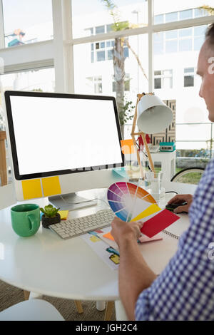 Designer holding color swatch while sitting at desk in office Banque D'Images