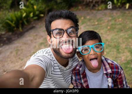 Portrait du père et fils portant des lunettes de soleil alors que sticking out tongue Banque D'Images