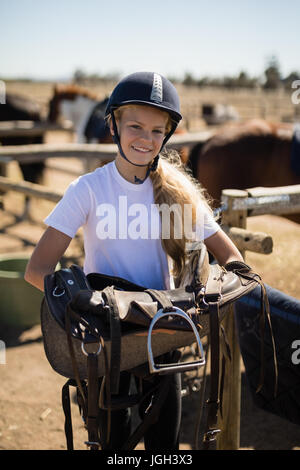 Smiling girl holding selle de cheval sur une journée ensoleillée Banque D'Images