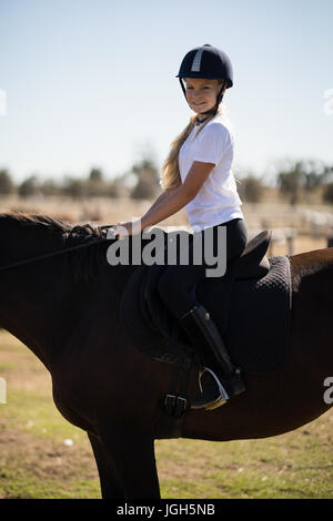 Portrait of smiling girl sitting on un cheval dans le ranch Banque D'Images