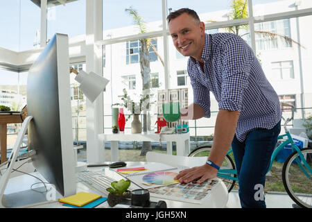 Portrait du designer holding coffee while standing at table in office Banque D'Images