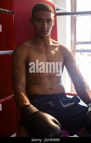 Portrait of smiling man sitting in ring de boxe au studio de remise en forme Banque D'Images