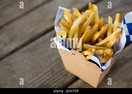 Frites avec du papier ciré dans un contenant sur le tableau Banque D'Images