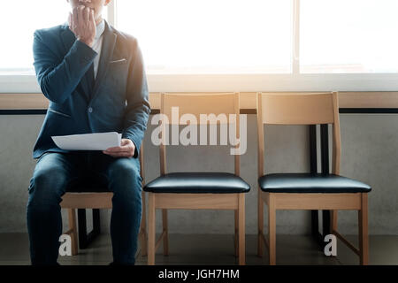 Young man pour l'entrevue d'être anxieux, sur une rangée de chaises Banque D'Images