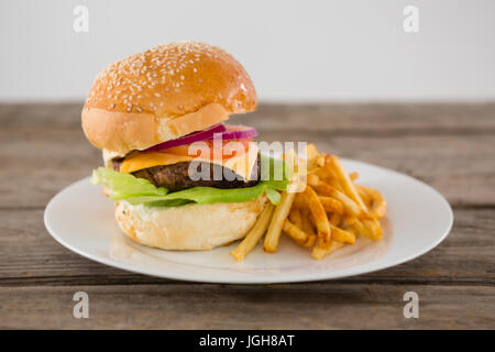 Cheeseburger accompagné de frites dans la plaque sur la table contre le mur Banque D'Images