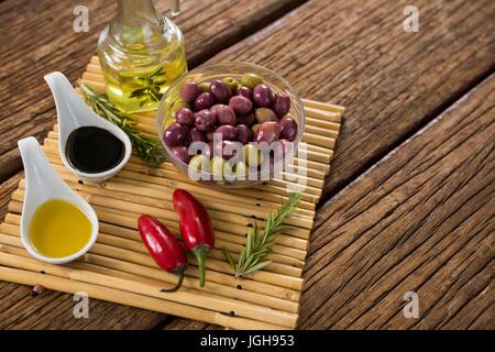 Olives marinées avec des ingrédients sur la table en bois Banque D'Images