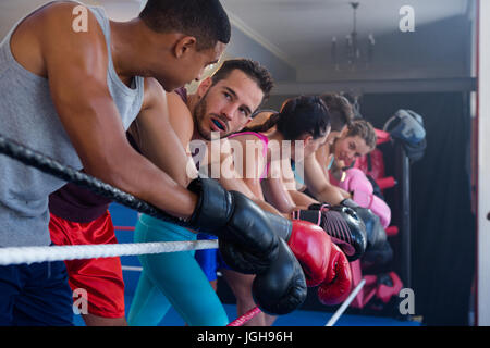 Fatigué des boxeurs masculins et féminins s'appuyant sur la corde dans l'anneau de boxe Banque D'Images